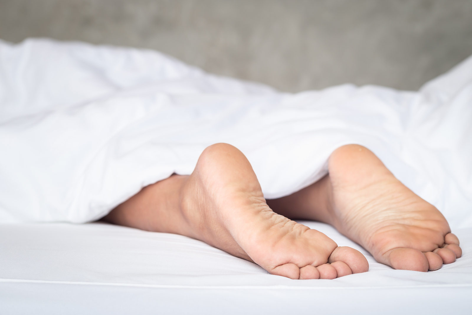 Close up feet of women on white bedding in the morning time