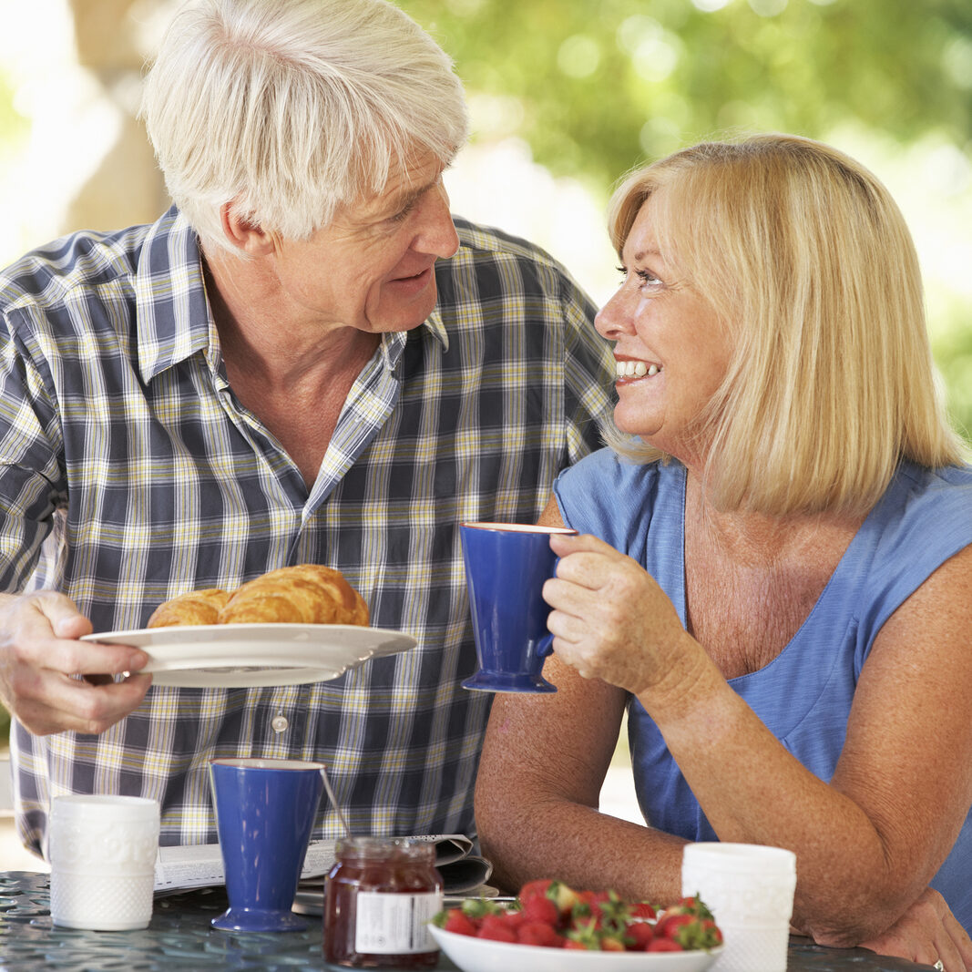 Senior couple eating breakfast outdoors